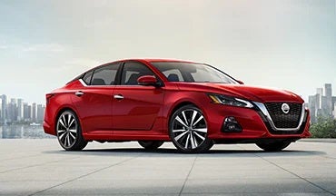 2023 Nissan Altima in red with city in background illustrating last year's 2022 model in Valley Nissan in Longmont CO