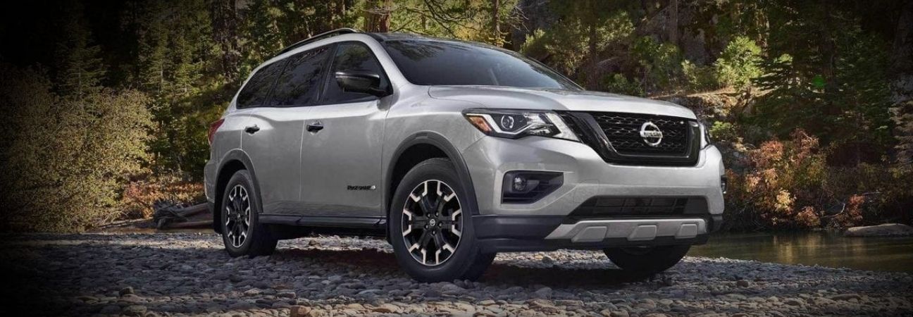 2019 Nissan Pathfinder driving by a river in the woods